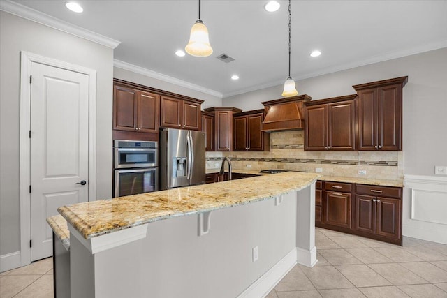 kitchen with visible vents, appliances with stainless steel finishes, a breakfast bar, hanging light fixtures, and a kitchen island with sink