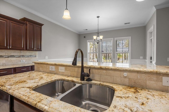 kitchen with light stone counters, decorative light fixtures, crown molding, backsplash, and a sink