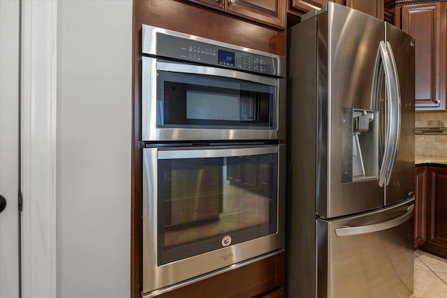 kitchen featuring light stone countertops, light tile patterned floors, stainless steel appliances, and decorative backsplash