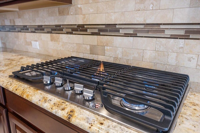 interior details featuring light stone countertops, stainless steel gas cooktop, and backsplash