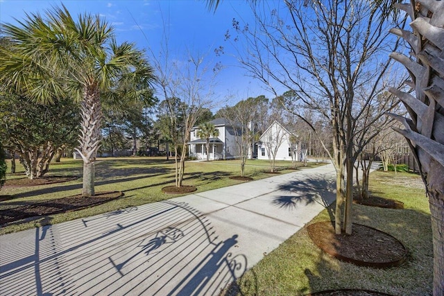 view of home's community featuring concrete driveway and a yard