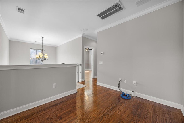 spare room featuring baseboards, visible vents, wood finished floors, and ornamental molding