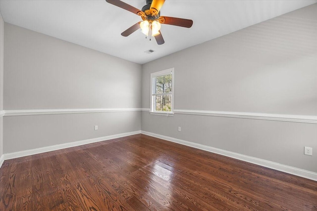 empty room with visible vents, dark wood-type flooring, a ceiling fan, and baseboards