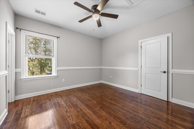 unfurnished room with attic access, visible vents, dark wood finished floors, and baseboards