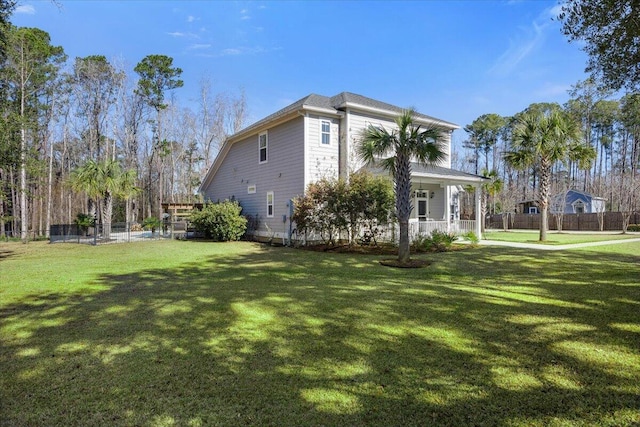 view of home's exterior featuring fence, a porch, and a lawn