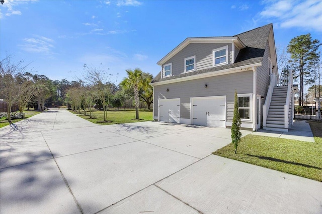 view of side of home featuring concrete driveway, a yard, stairway, and an attached garage