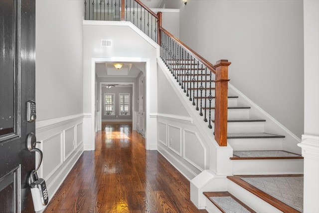 foyer featuring a wainscoted wall, visible vents, dark wood finished floors, and a decorative wall