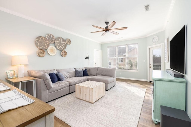 living area with ceiling fan, visible vents, light wood finished floors, and ornamental molding