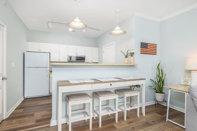 kitchen with stainless steel microwave, dark wood-style flooring, white cabinets, and freestanding refrigerator