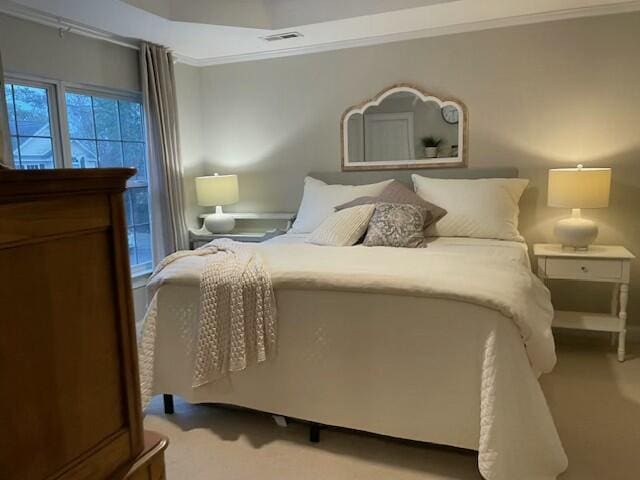 bedroom featuring visible vents, ornamental molding, and carpet flooring