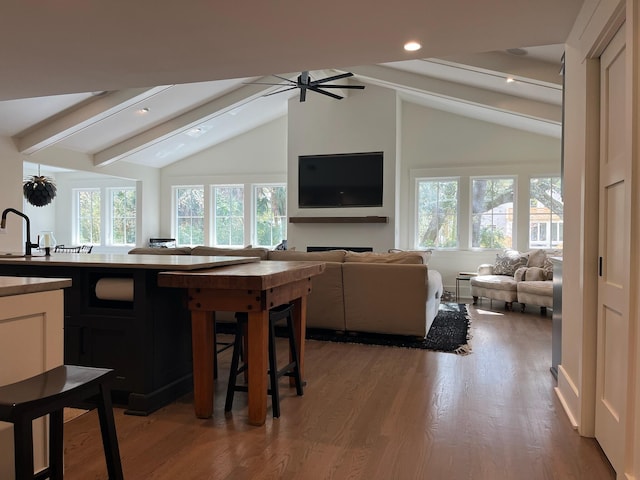 kitchen featuring a wealth of natural light, wood finished floors, open floor plan, and vaulted ceiling with beams