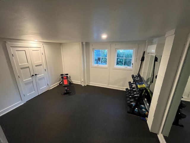 workout room featuring an AC wall unit and baseboards