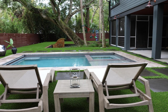 view of pool featuring a yard, a fenced backyard, a pool with connected hot tub, a playground, and a patio area