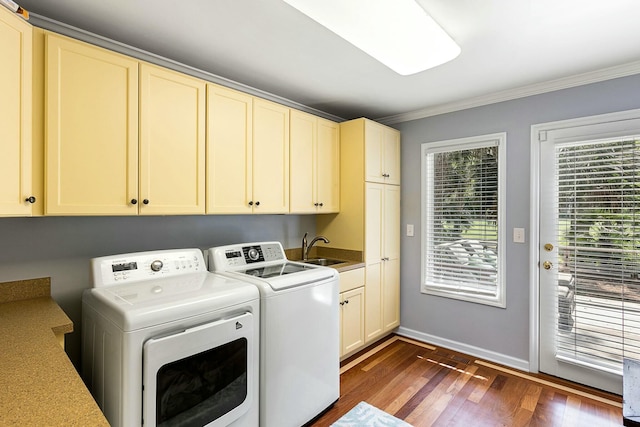 laundry room featuring dark wood finished floors, ornamental molding, a sink, washing machine and clothes dryer, and cabinet space