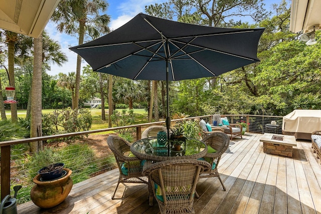 wooden deck featuring outdoor dining space and an outdoor living space with a fire pit