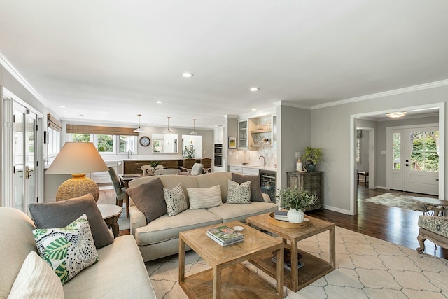 living area with plenty of natural light, wood finished floors, ornamental molding, and wine cooler