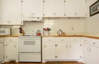 kitchen featuring backsplash, white cabinetry, and white appliances