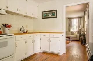 kitchen with white cabinets, stove, wood-type flooring, and range hood