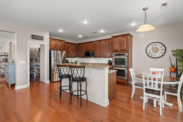 7030 Billberry St, Hanahan, SC 29410 - kitchen with appliances with stainless steel finishes, wood finished floors, recessed lighting, a breakfast bar area, and a kitchen island with sink
