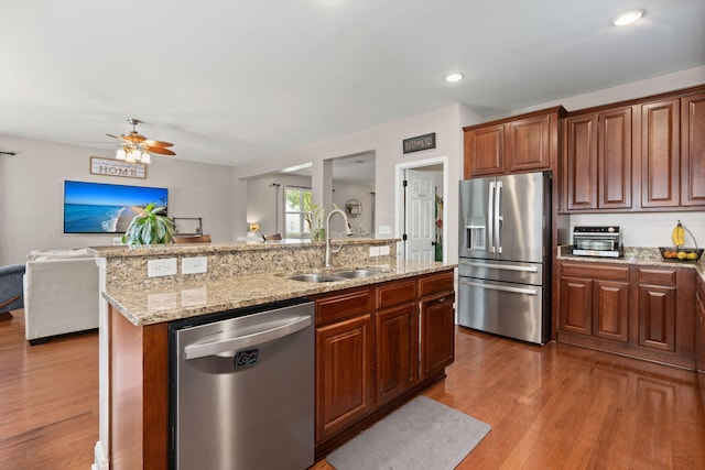7030 Billberry St, Hanahan, SC 29410 - kitchen featuring appliances with stainless steel finishes, open floor plan, wood finished floors, ceiling fan, and a center island with sink