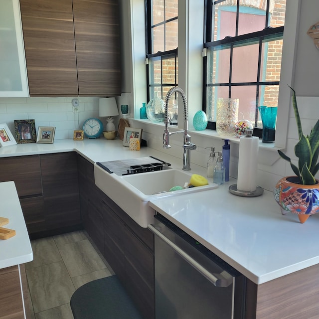 kitchen with light countertops, dishwasher, modern cabinets, tasteful backsplash, and a sink