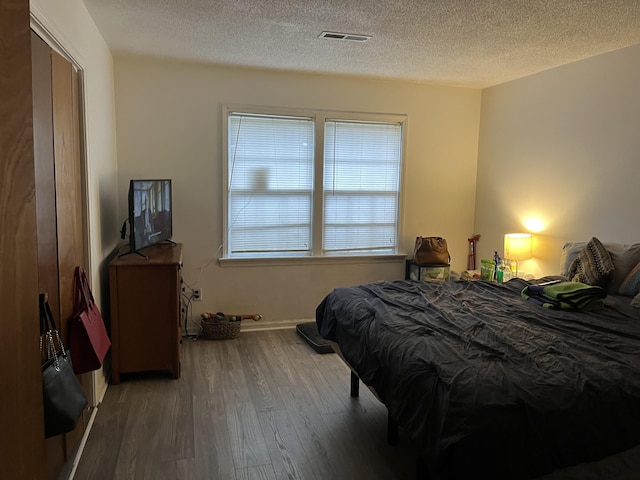 bedroom with hardwood / wood-style floors and a textured ceiling