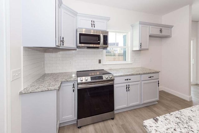 kitchen with white cabinets, light wood-type flooring, stainless steel appliances, and light stone countertops