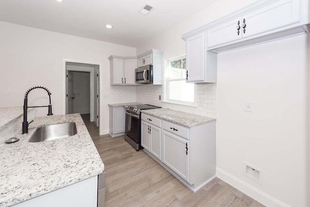 kitchen featuring light stone countertops, stainless steel appliances, sink, white cabinets, and light hardwood / wood-style floors