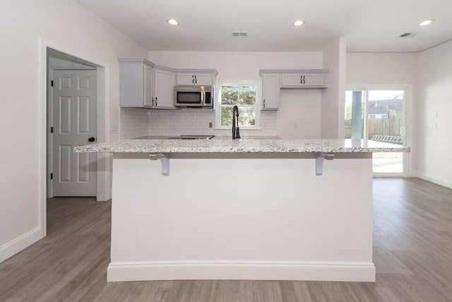 kitchen with light hardwood / wood-style floors, light stone counters, and a healthy amount of sunlight