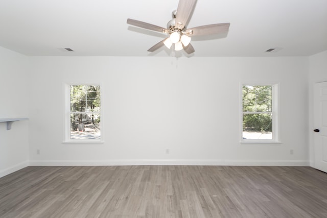 empty room with ceiling fan, a healthy amount of sunlight, and light hardwood / wood-style floors