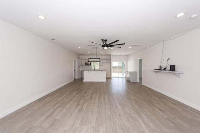 unfurnished living room featuring light wood-type flooring and ceiling fan