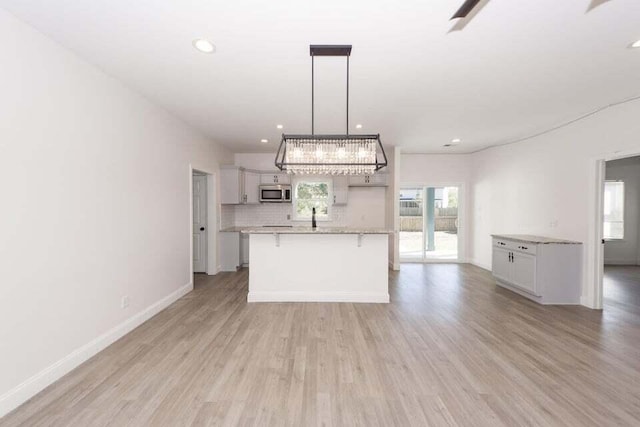 kitchen with a breakfast bar area, hanging light fixtures, and light hardwood / wood-style floors