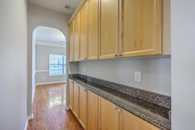 9379 Harroway Rd, Summerville, SC 29485 - kitchen featuring light brown cabinetry, dark stone countertops, wood finished floors, visible vents, and arched walkways