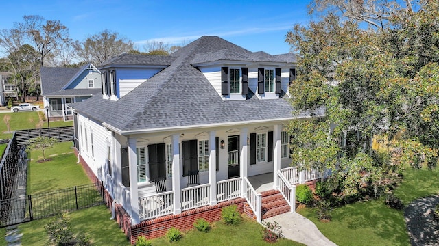 view of front of house featuring a front lawn, a fenced backyard, covered porch, and a shingled roof