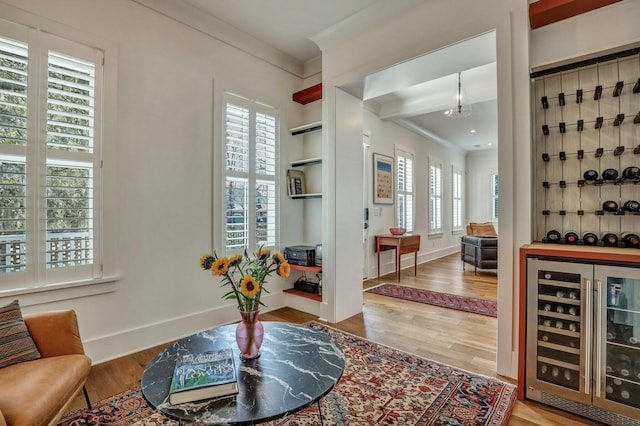 interior space with baseboards, wine cooler, wood finished floors, and crown molding