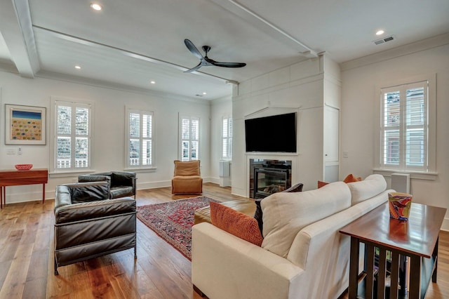 living area featuring a wealth of natural light, visible vents, a ceiling fan, and light wood finished floors