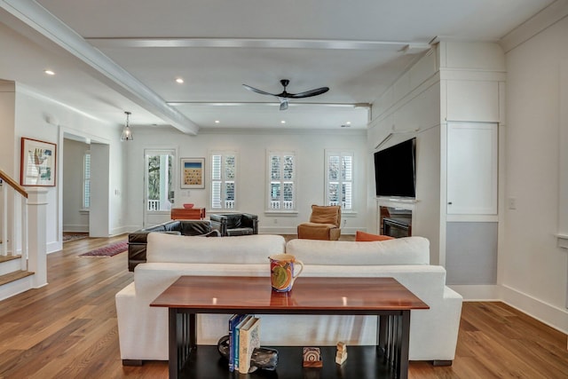 living room with light wood finished floors, ceiling fan, stairway, recessed lighting, and a glass covered fireplace