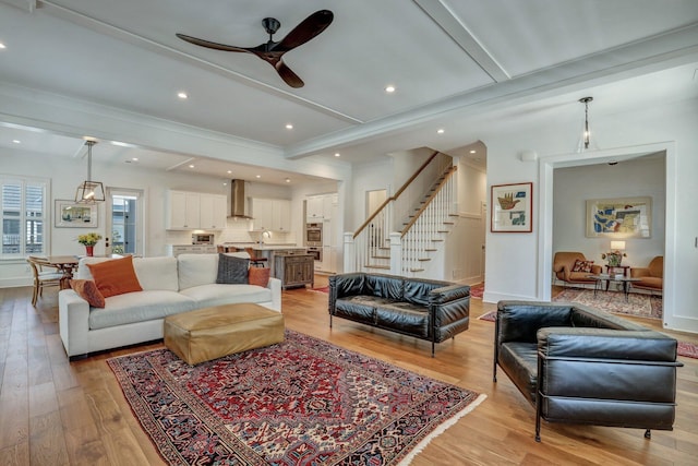 living room featuring light wood finished floors, ceiling fan, stairway, beam ceiling, and recessed lighting