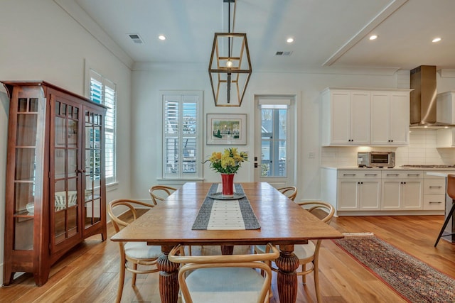 dining space with crown molding, a toaster, light wood-style floors, and visible vents