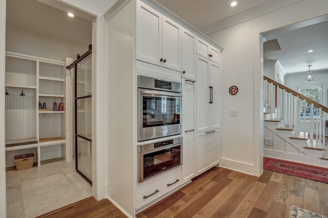 kitchen with wood finished floors, recessed lighting, white cabinets, crown molding, and baseboards