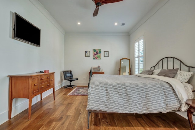 bedroom featuring crown molding, wood finished floors, baseboards, and ceiling fan