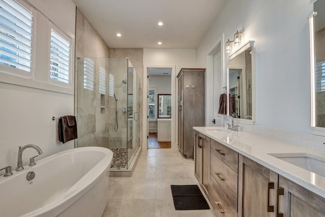 bathroom with double vanity, a soaking tub, a shower stall, and a sink