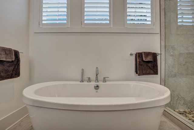 bathroom with a shower stall and a freestanding bath