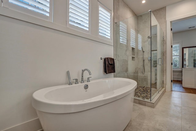 full bath featuring recessed lighting, a freestanding tub, and a shower stall