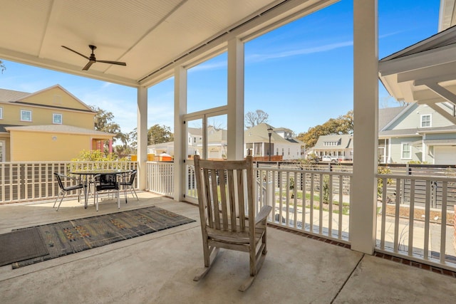 sunroom / solarium with a residential view, a wealth of natural light, and ceiling fan