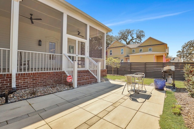 view of patio / terrace with a ceiling fan, fence, and a sunroom