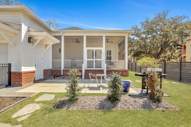 exterior space featuring brick siding, ceiling fan, fence, a yard, and a patio area