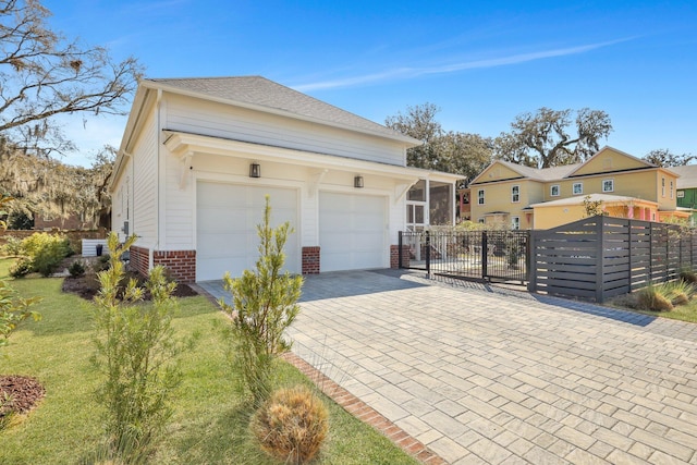 view of front of home featuring a front lawn, decorative driveway, fence, an attached garage, and brick siding