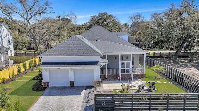 view of front of home featuring driveway, roof with shingles, a front yard, brick siding, and fence private yard