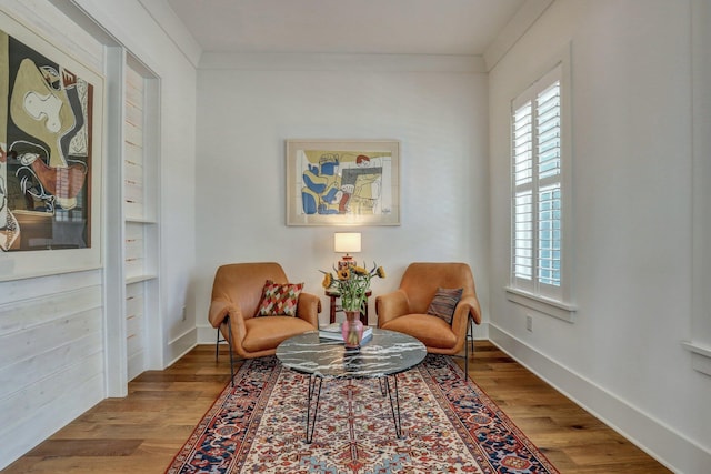 living area with baseboards, a healthy amount of sunlight, wood finished floors, and ornamental molding